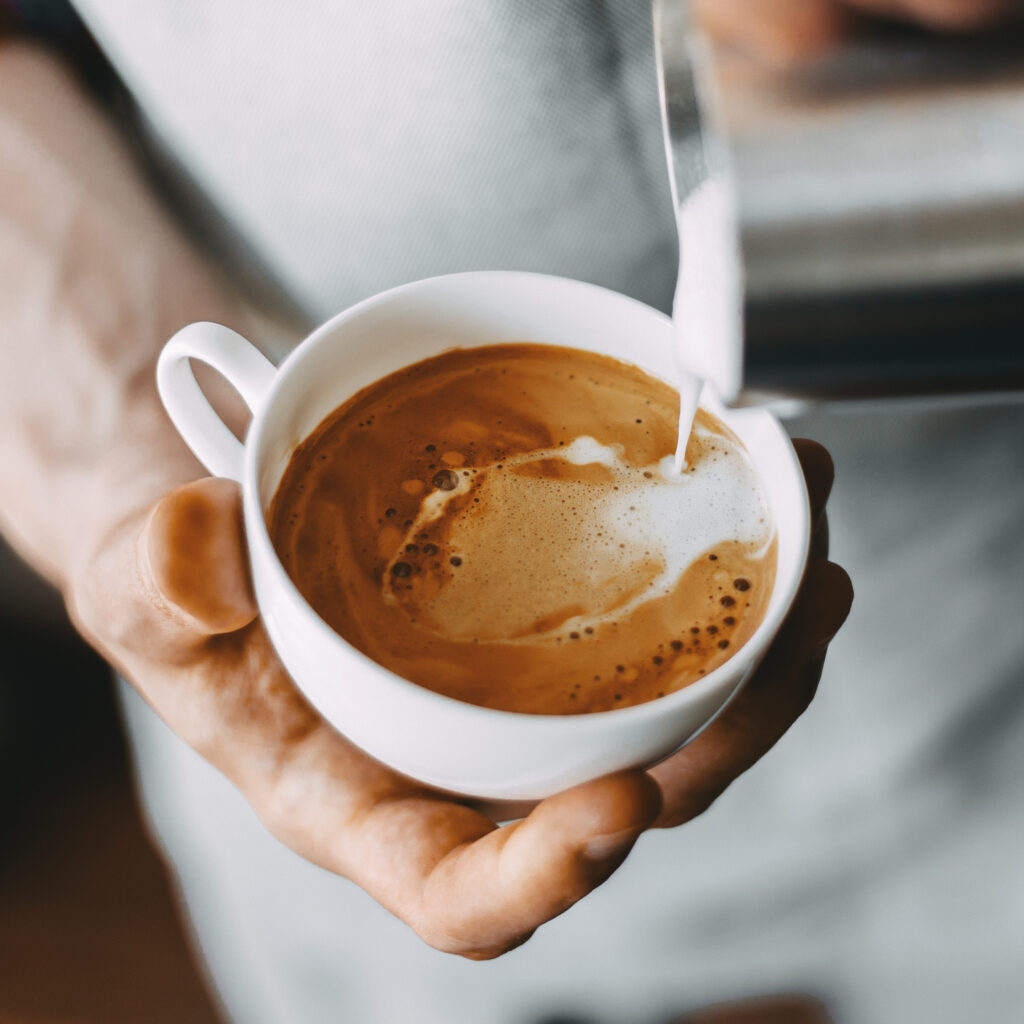 Barista sirviendo leche en el café